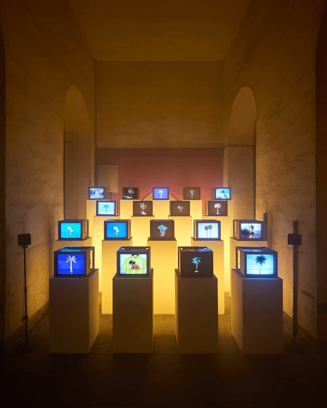 Wall of vintage televisions in a warmly lit gallery